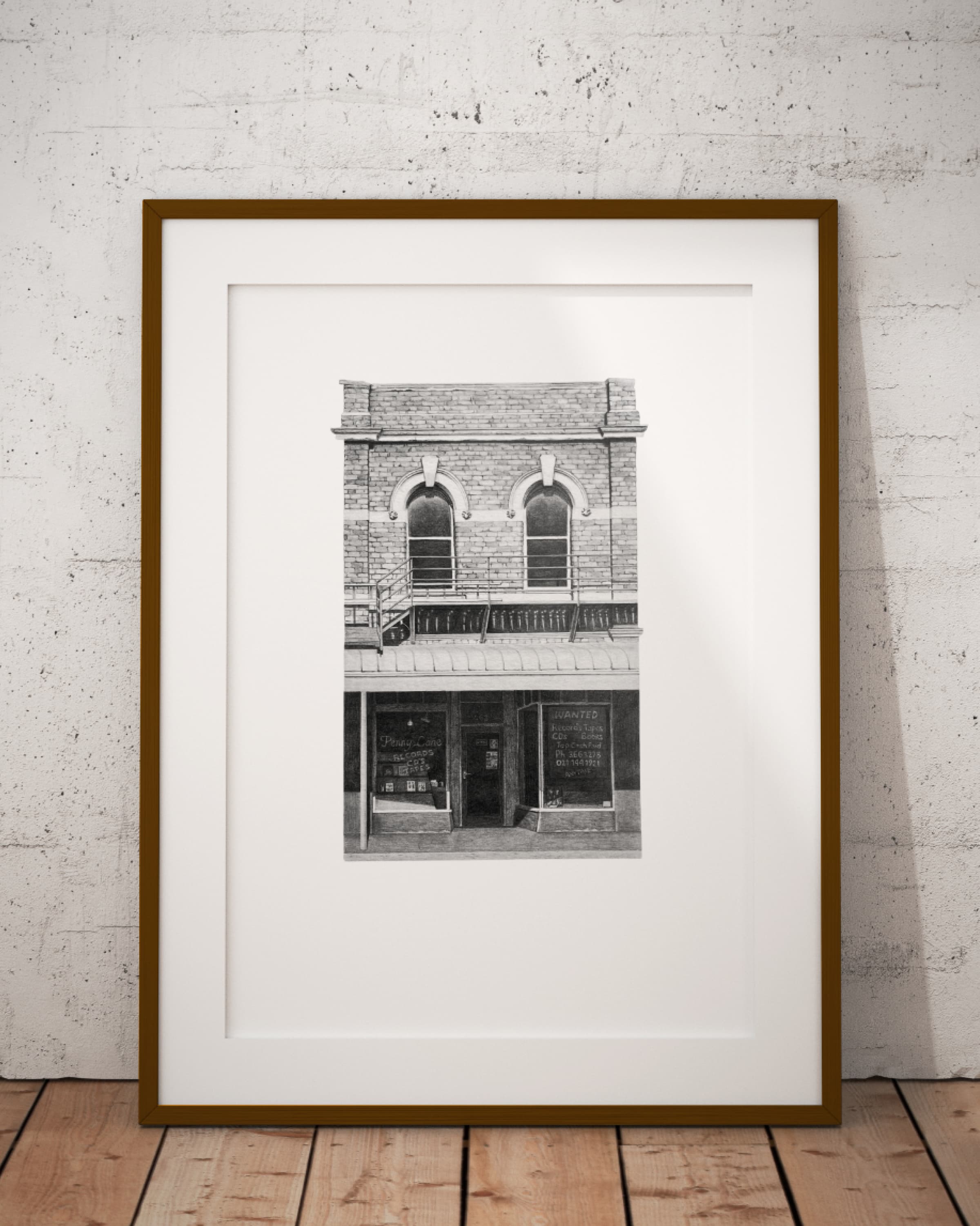 The Penny Lane print in a slim wooden frame with a white mount, leaning against a concrete wall